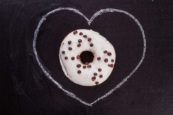 Coração desenhado e donut em fundo preto . — Fotografia de Stock