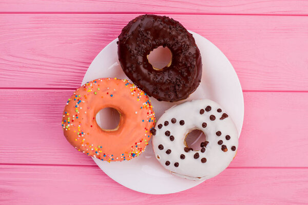 Three donuts on plate, top view.