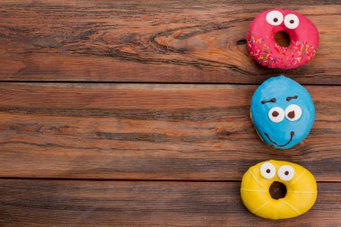 Ahşap arka plan üzerinde üç komik donut.