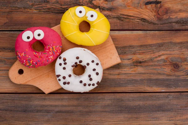 Engraçado decorado donuts no fundo de madeira . — Fotografia de Stock