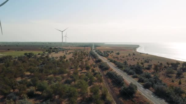 Větrná energetická generátory proti modrému nebi, moři a polím. — Stock video