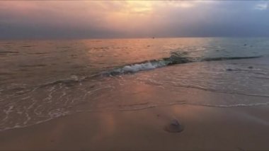 Arka planda el sallayan denizin üzerinde gün batımı gökyüzü.