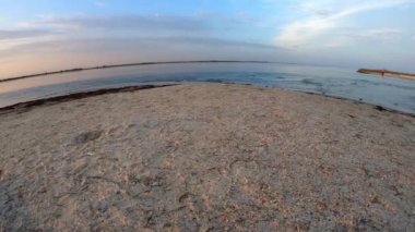 Kumlu plaj, deniz dalgaları ve mavi gökyüzü.