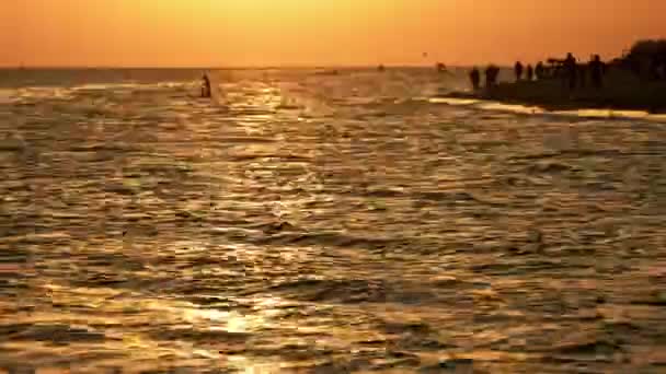 Vågor på en havsstrand vid solnedgången. — Stockvideo