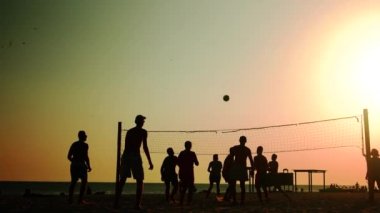 Gün batımında sahilde valleyball oyuncularının siluetleri.