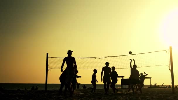 Silhouetten von Menschen, die bei Sonnenuntergang Beachvolleyball spielen. — Stockvideo