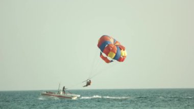Yaz günü deniz üzerinde paraşütle uçan çift.