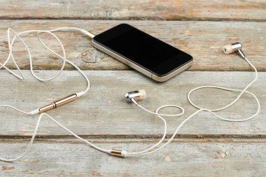 Ahşap tahtalarda kulaklıklı akıllı telefon.