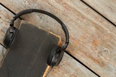 Ahşap arka plan üzerinde kitap ile Kulaklıklar.