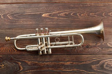 Trumpet on brown wooden background. clipart