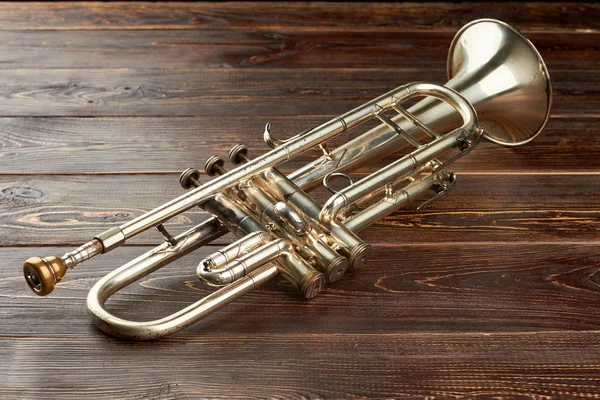 Shiny trumpet on brown wooden background. — Stock Photo, Image