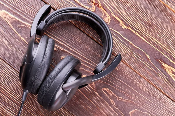 Headphones on brown textured wood.