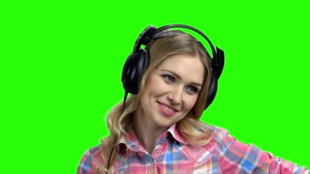 Young happy woman using headphones on green screen. — Stock Video