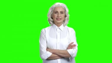 Gülümseyen yaşlı kadın yeşil ekranda kameraya bakıyor.