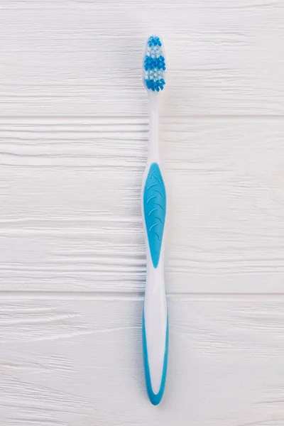 Blue tooth brush on white wooden background.