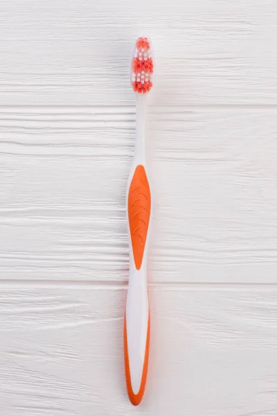Cepillo de dientes naranja sobre fondo de madera blanco . — Foto de Stock