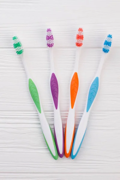 Set of colorful tooth brushes on white wooden background. — Stock Photo, Image