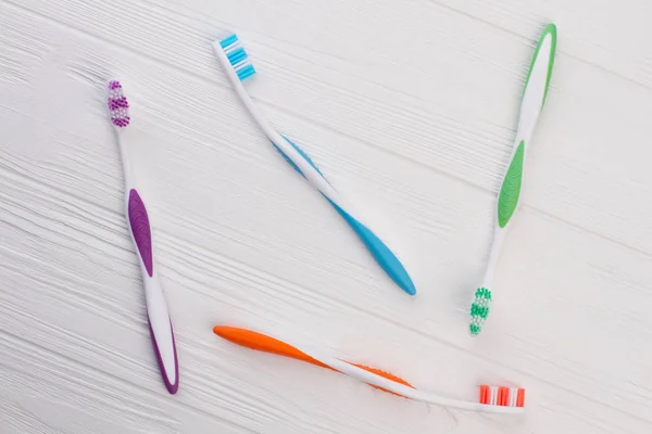 Colored tooth brushes on white wooden background. — Stock Photo, Image