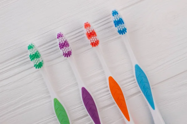 Different colors toothbrushes on wooden background. — Stock Photo, Image