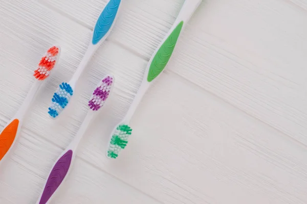 Group of four soft toothbrushes on wooden background. — Stock Photo, Image
