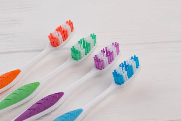 Four different tooth brushes on wooden background. — Stock Photo, Image