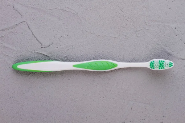 Nova escova de dentes no fundo cinza . — Fotografia de Stock