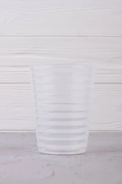 Άδειο πλαστικό γυαλί σε λευκό ξύλινο φόντο. — Φωτογραφία Αρχείου