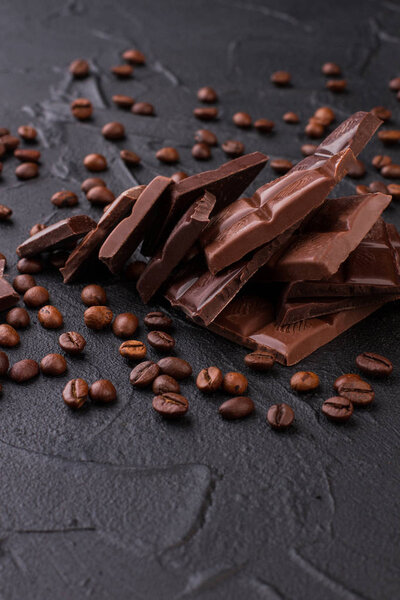 Chocolate and coffee beans on black concrete background.