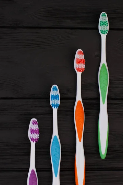 Group of tooth brushes on black wooden table. — Stock Photo, Image
