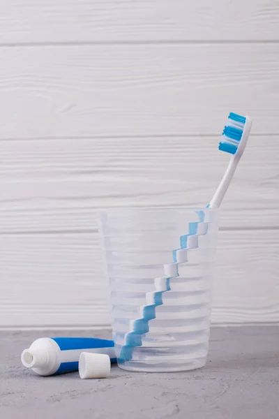 Tube of toothpaste and glass with toothbrush. — Stock Photo, Image