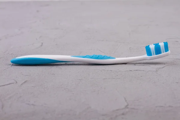 Blue toothbrush on grey textured background. — Stock Photo, Image