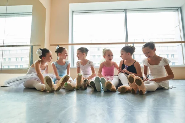 Jonge gelukkige ballerina's zittend op de vloer en praten. — Stockfoto