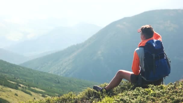 Homem caminhante sentado na colina e desfrutando de montanhas . — Vídeo de Stock