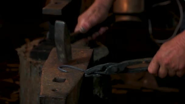 Кузнец в кузнице бьет раскаленный металл на наковальне молотком . — стоковое видео