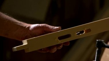 Carpenter holding wooden plank with carved holes.