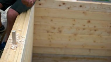 Ahşap inşaatta çekiçle çalışan inşaatçı.