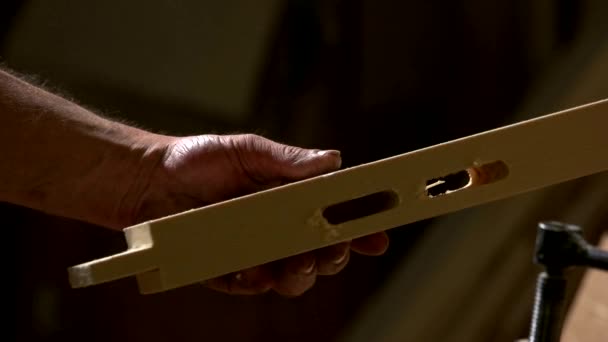 Carpenter holding wooden plank with carved holes. — Stock videók