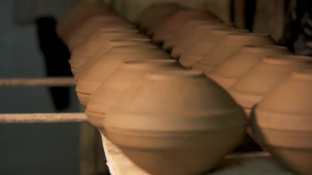 Ceramic bowls on wooden shelves in pottery workshop. — Stock Video