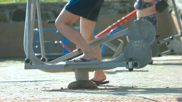 Hombre piernas de entrenamiento en la máquina de gimnasio al aire libre . — Vídeos de Stock