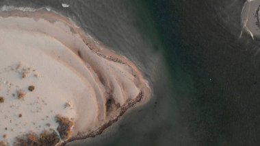 Dalgalar kumsalda yuvarlanıyor, yukarıdan manzara.