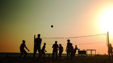 Gün batımında plaj voleybolcuları.