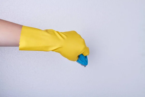 Mão com luva de borracha amarela segurando escova azul . — Fotografia de Stock