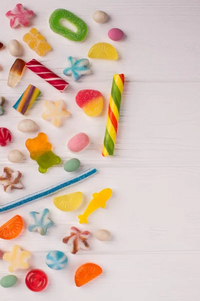 Border from colorful sweets on white wood. — Stock Photo, Image