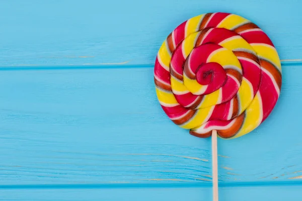 Colorful lollipop caramel on stick over blue background.