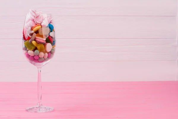 Wine glass filled with colorful candies.