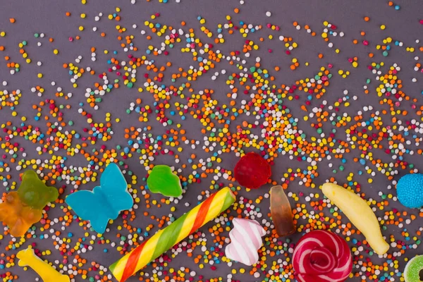 Jelly candies and sprinkles on dark background. — Stock Photo, Image
