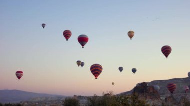 Kayalık dağların üzerinde sıcak hava balonları.