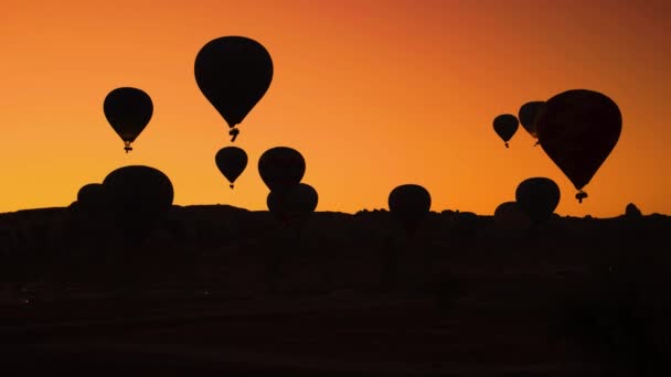 Silhouetten van hete lucht ballonnen op oranje zonsondergang hemel achtergrond. — Stockvideo