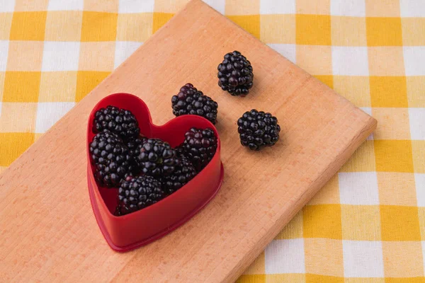 Heart-shaped form filled with natural fresh ripe blackberries. — Stock Photo, Image