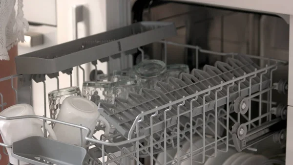 Close up open dishwasher with clean cups.